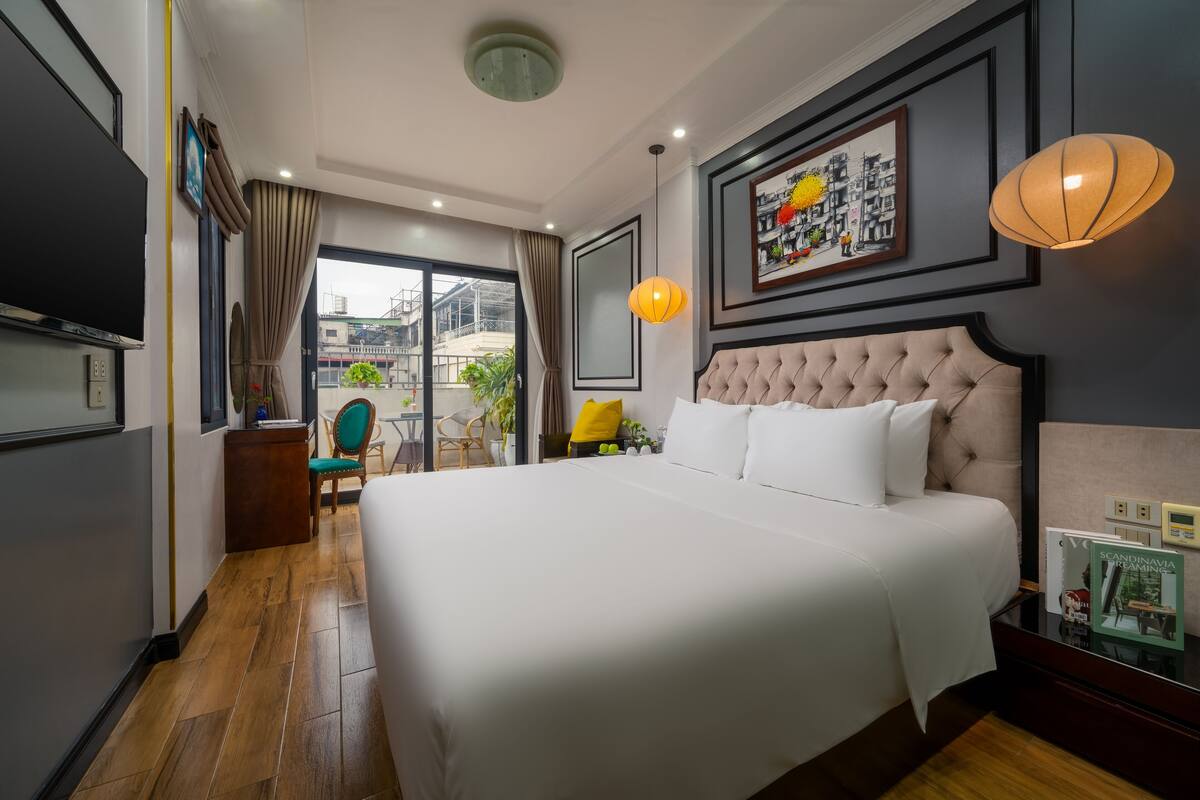 A hotel room with a large bed, a television, a desk, and a view of the outdoors.