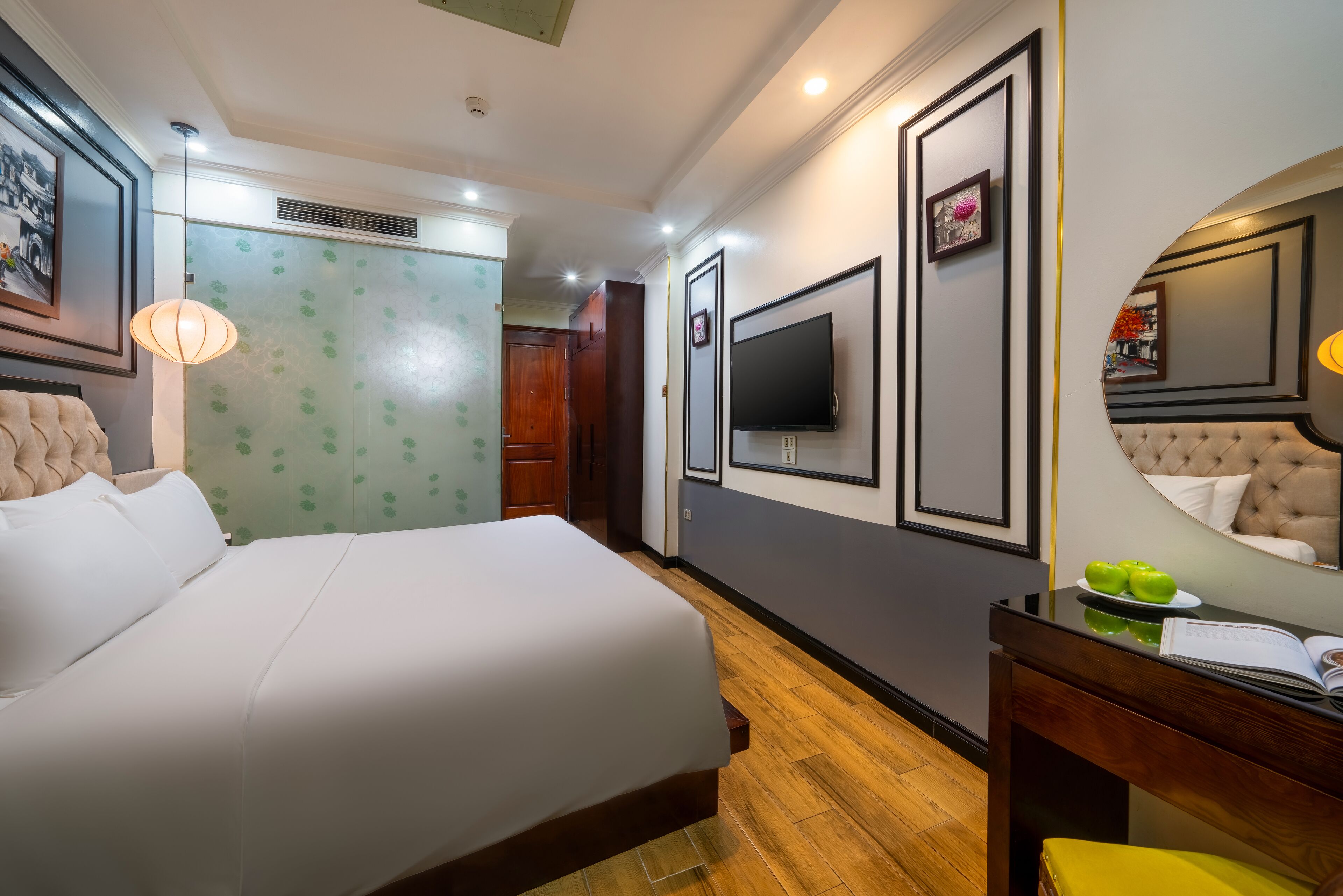 Une chambre d’hôtel avec un grand lit, un téléviseur à écran plat, un miroir et un bureau en bois.