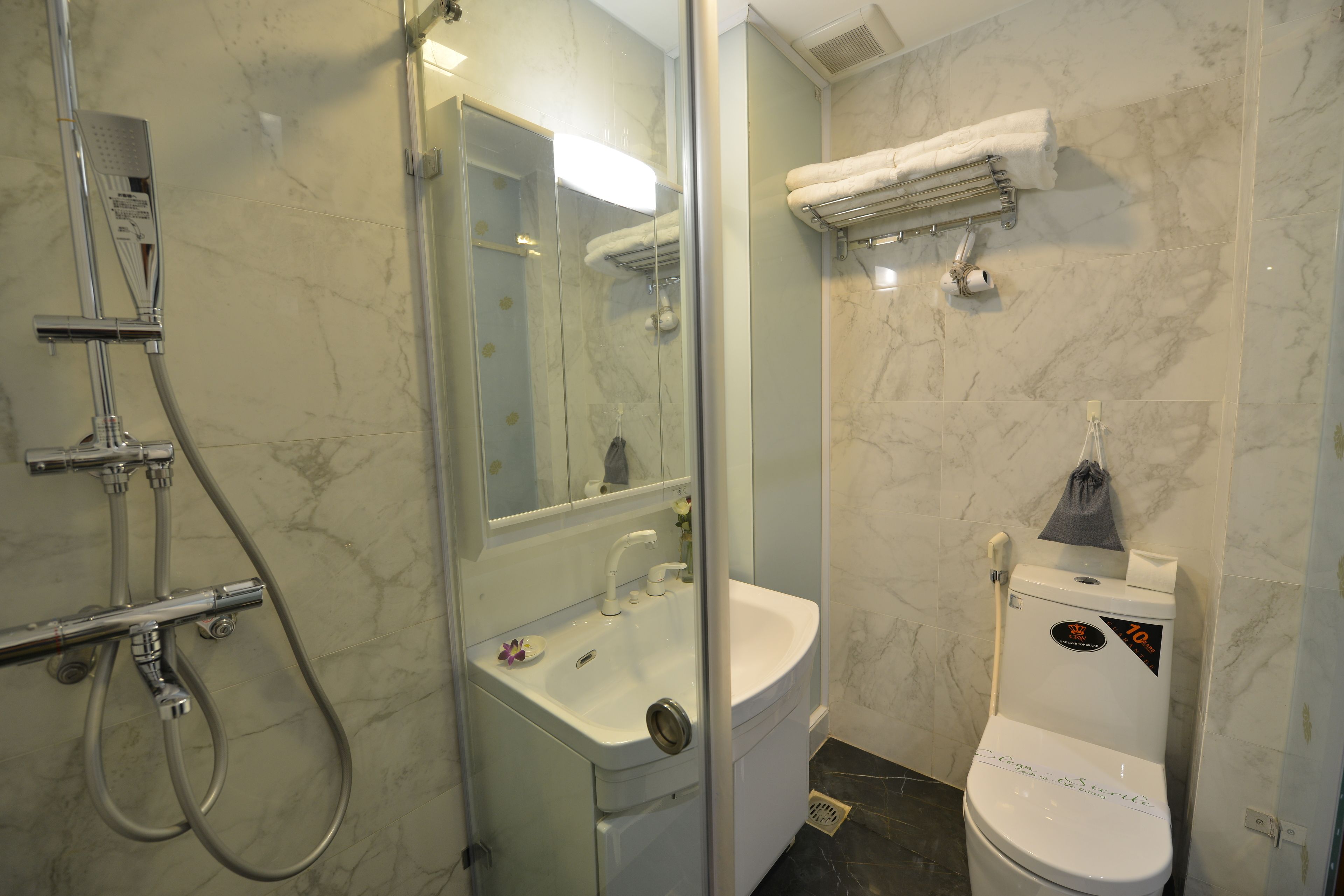 A bathroom with a glass-enclosed shower, a sink, and a toilet.