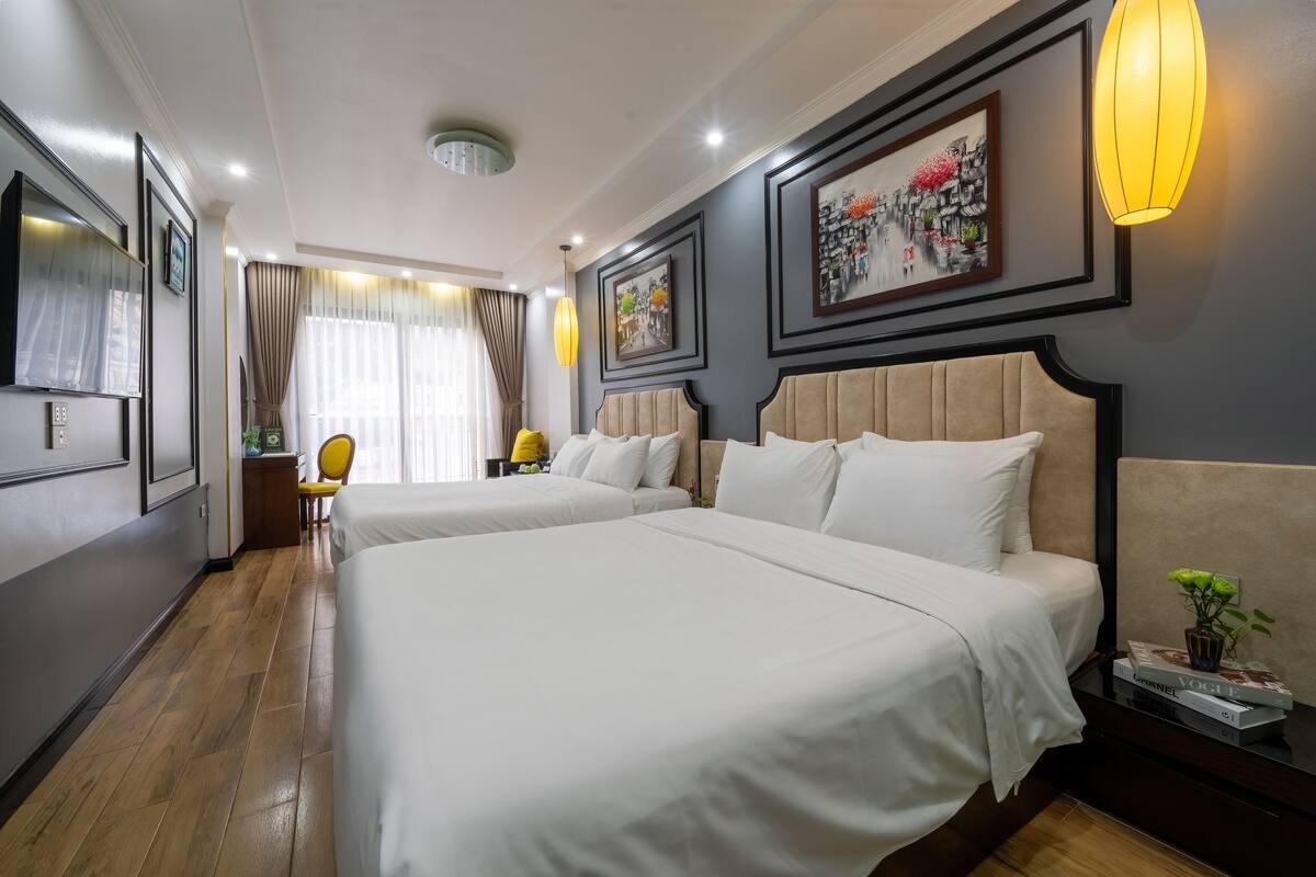 A hotel room with two beds, a desk, a chair, and artwork on the walls.