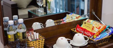 A hotel reception area with a coffee station, water bottles, snacks, and a sign for room service.