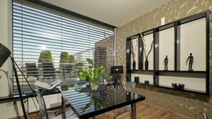 Un moderno comedor con una mesa de vidrio, sillas y vistas de la ciudad a través de amplios ventanales.