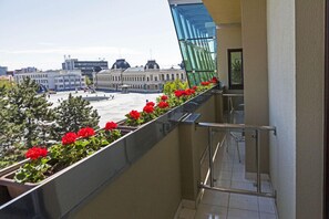Un balcón con flores rojas y vistas a un edificio histórico.