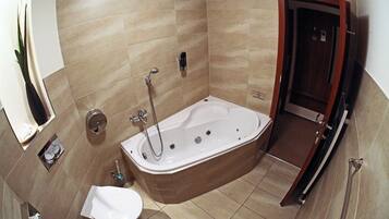 A bathroom with a bathtub, a toilet, and a shower area.
