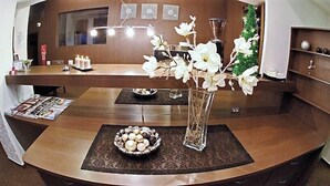 Una zona de recepción con un mostrador de madera, un jarrón con flores blancas y un cuenco con adornos.