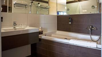 Un baño moderno con un espejo grande, una bañera y un tocador con lavabo.