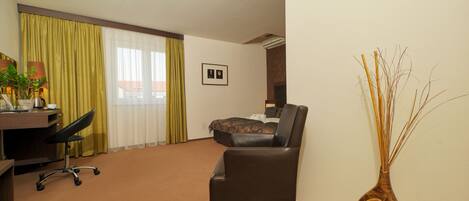 A hotel room with a desk, a chair, a bed, and a decorative vase.