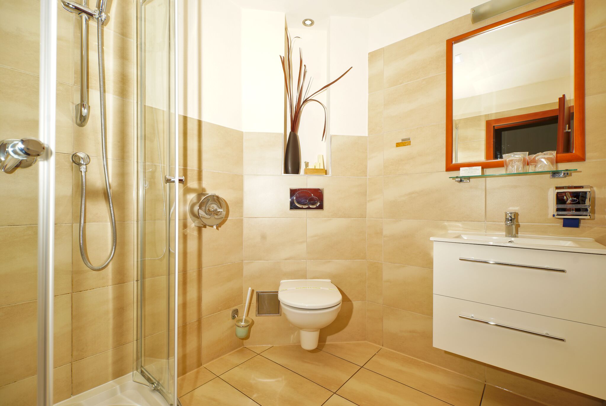 A bathroom with a glass shower enclosure, a toilet, and a vanity with drawers.