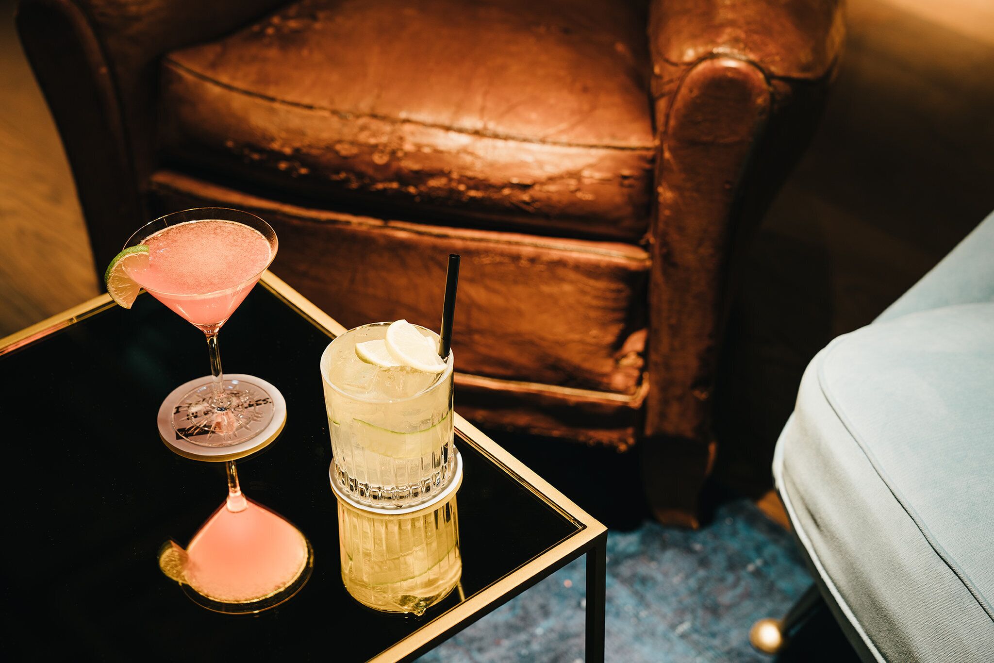 Lasipöydällä on cocktail-lasi, ja taustalla näkyy tuoli ja sohva.