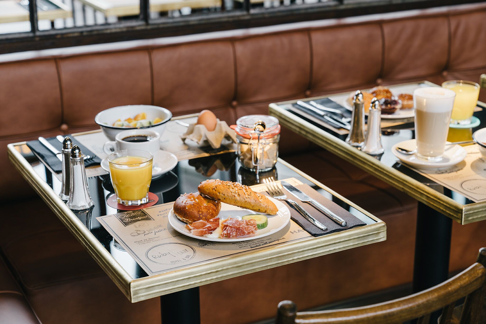 A dining table with breakfast items, a menu, and a cup of coffee.