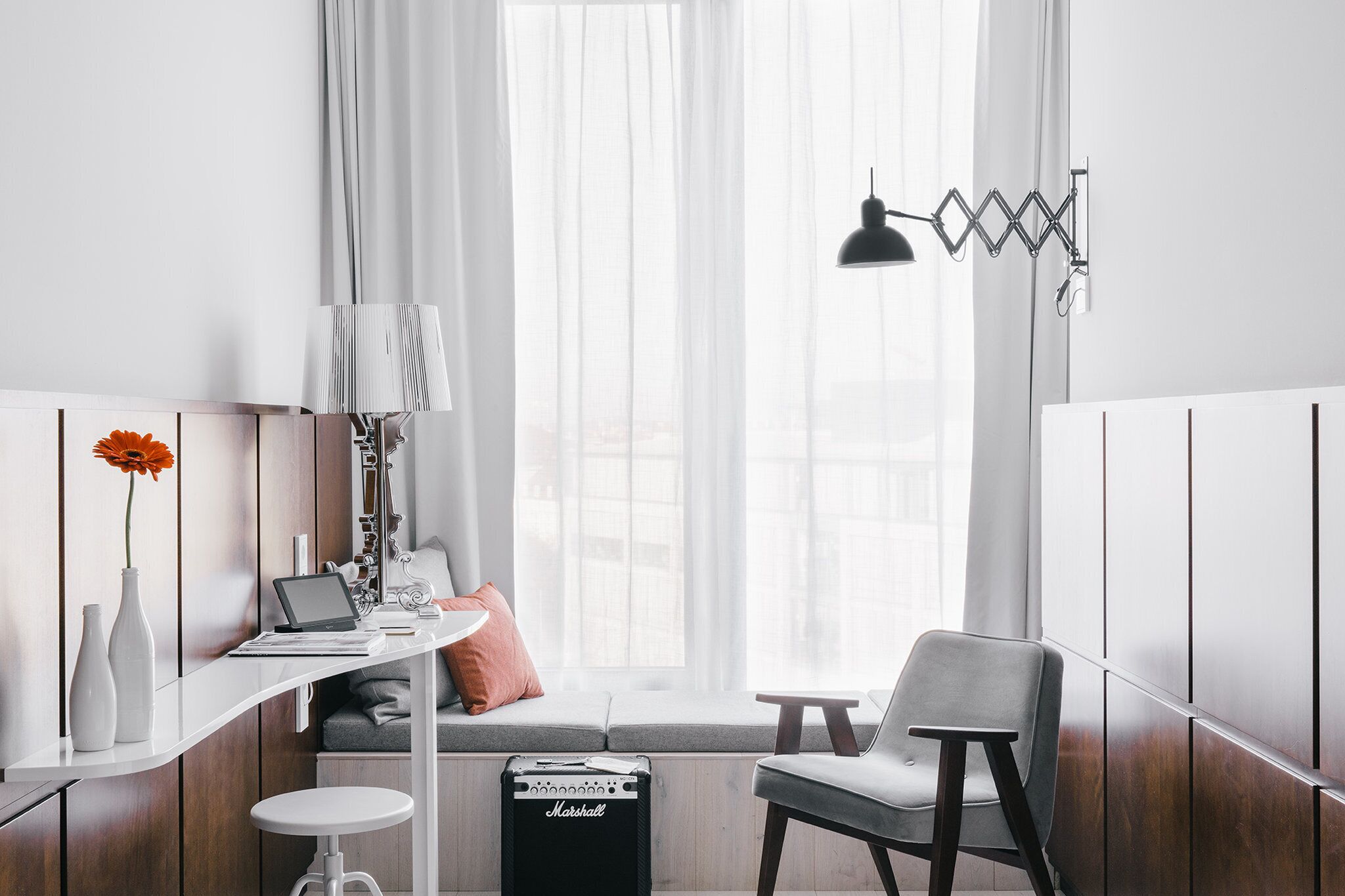 Una habitación moderna con escritorio, ordenador portátil, lámpara, silla y altavoz.