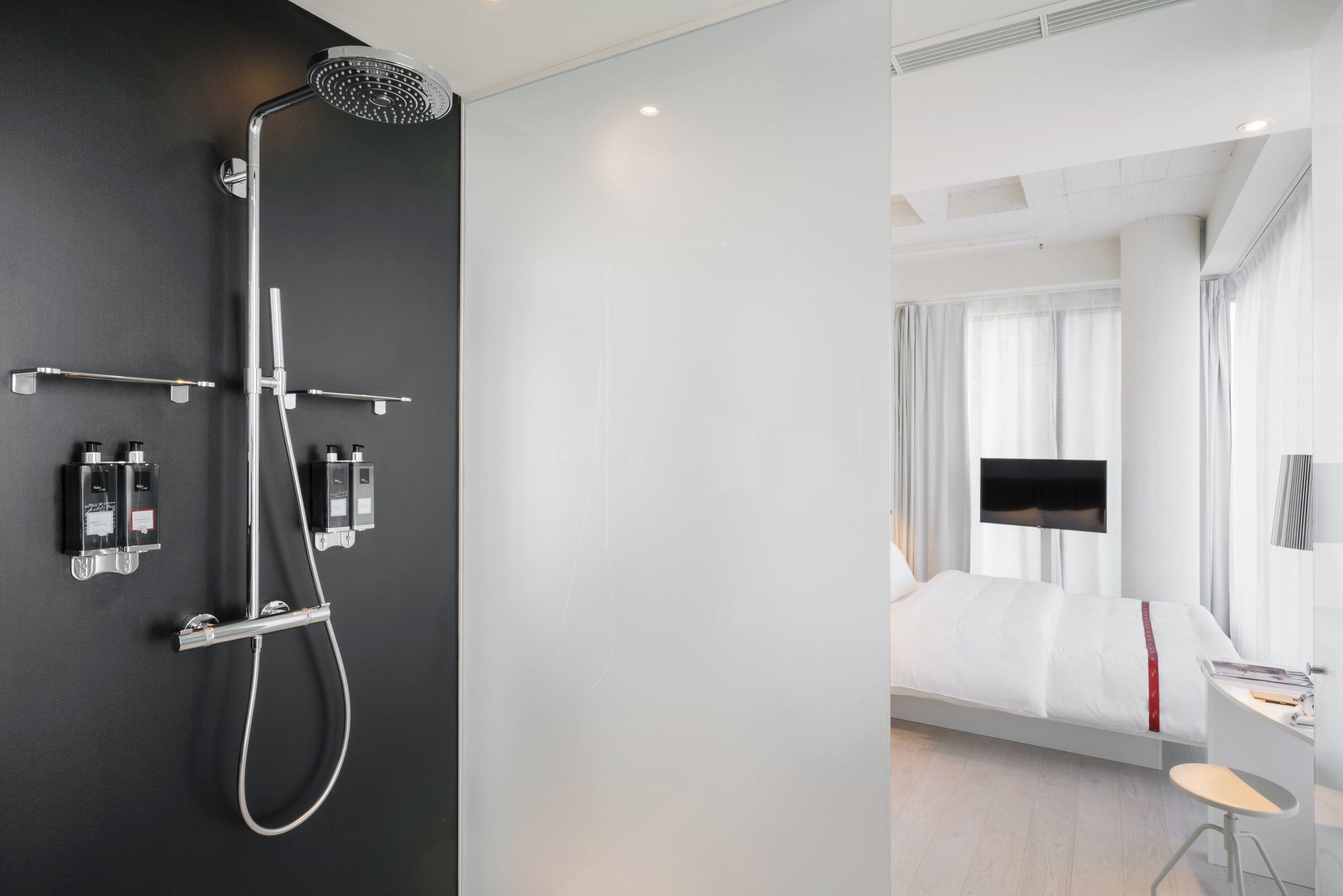 A modern bathroom with a shower, two hand dryers, and a towel rack.