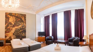 A hotel room with a bed, two armchairs, a TV, a painting, and a chandelier. - Safestay Berlin Kurfurstendamm (Berlin)