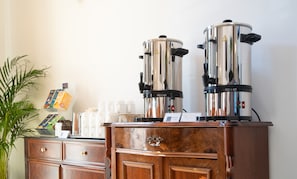 Two coffee machines on a wooden cabinet, a plant, and a shelf with coffee products. - Safestay Berlin Kurfurstendamm (Berlin)