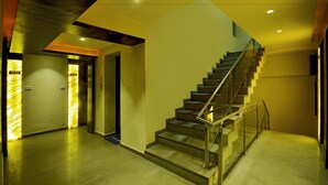 Un interior moderno con una escalera, ascensor y un pasillo con paredes iluminadas.