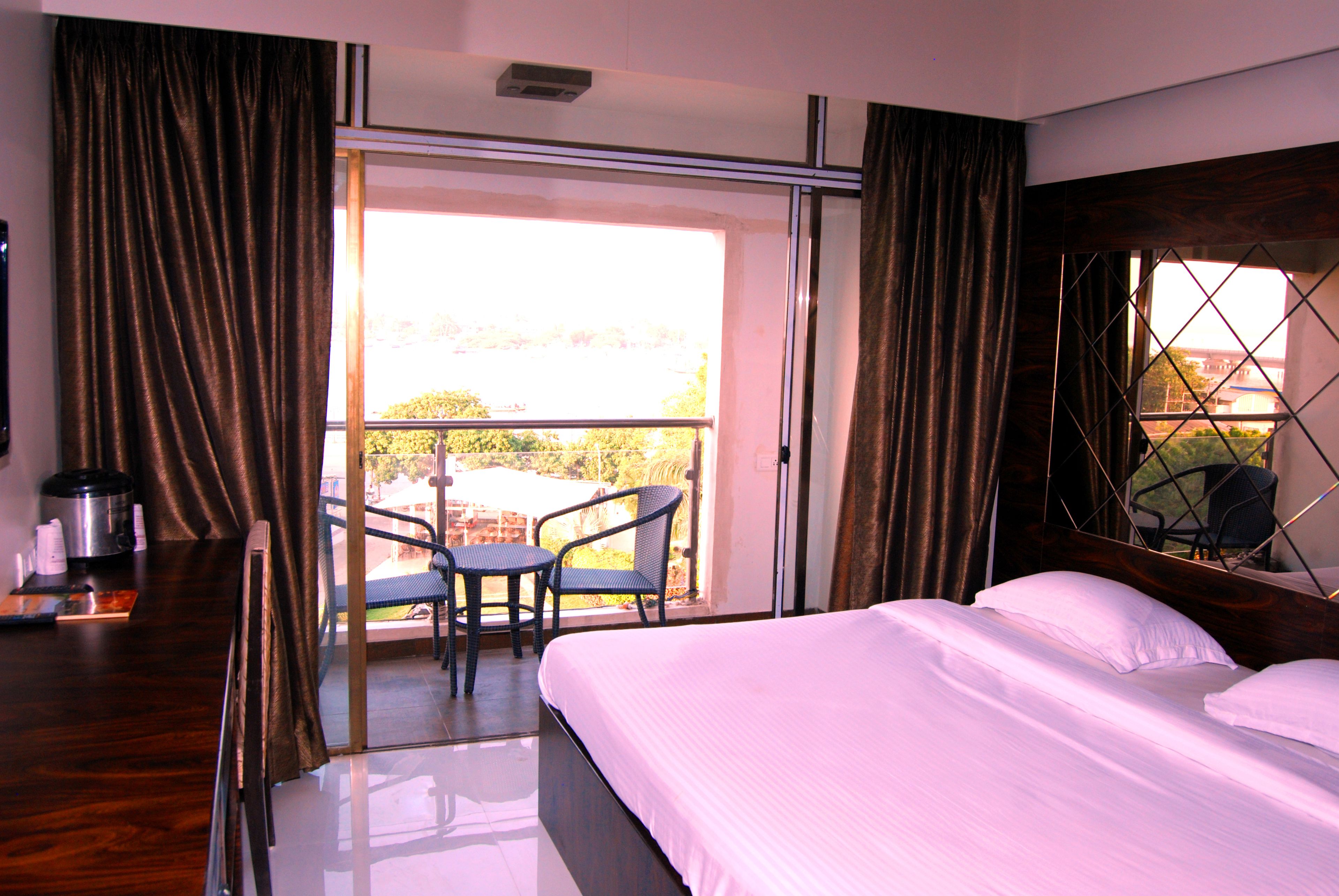 A hotel room with a bed, a table with chairs, and a view of the outdoors.