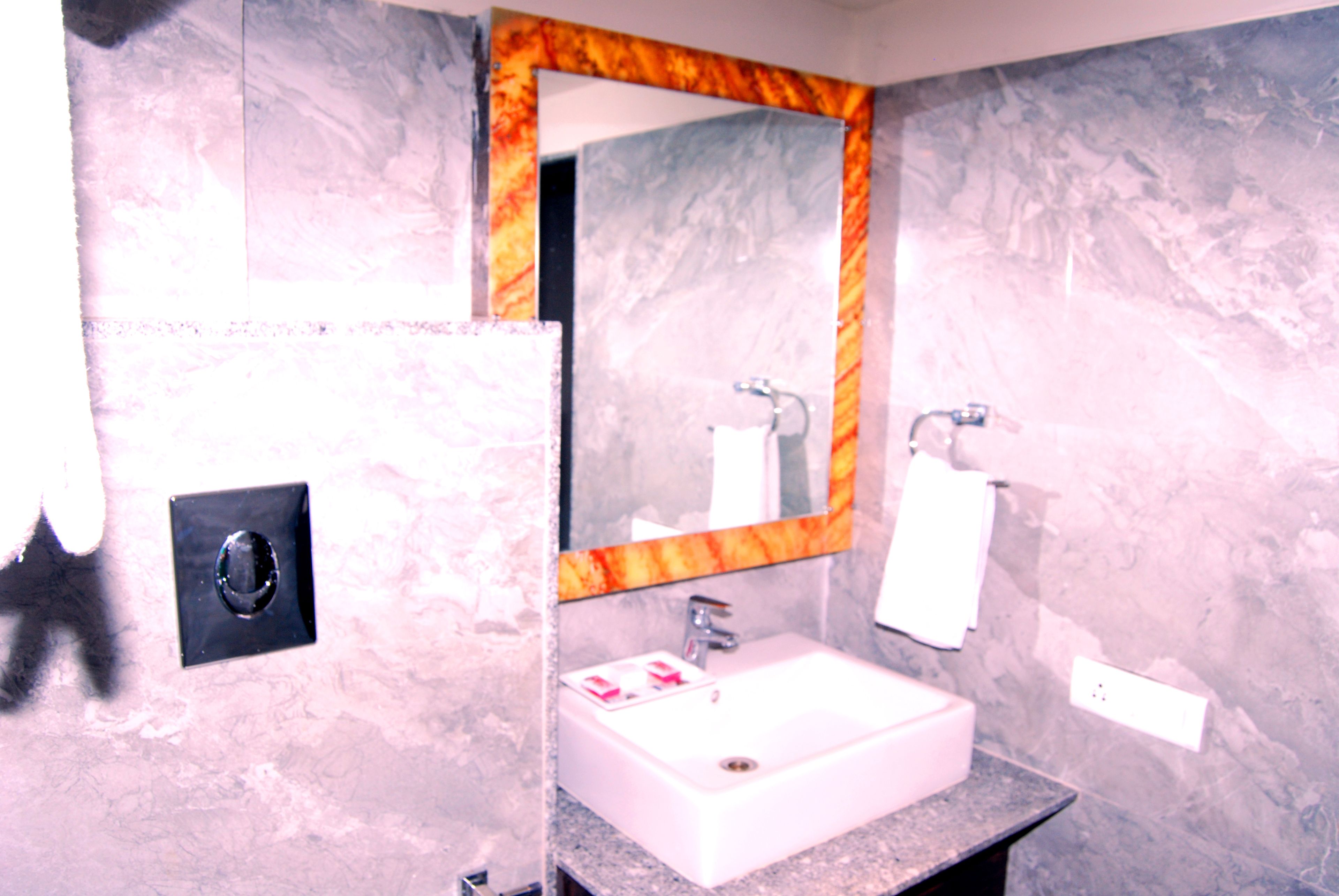 A bathroom with a marble sink, a mirror with a marble frame, and a towel hanging on the wall.