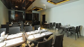 Comedor con varias mesas y sillas, con vajilla y cubiertos.