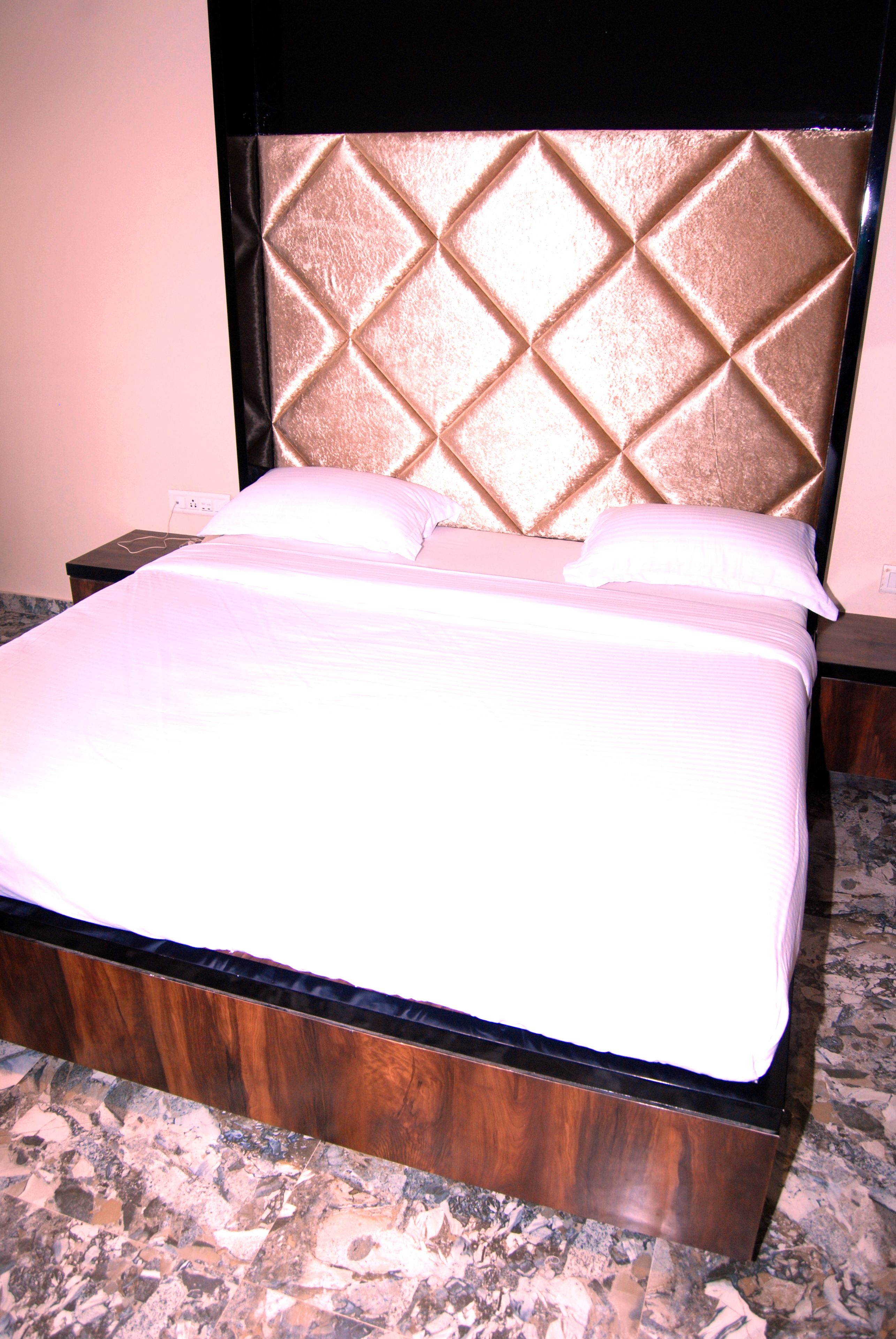 Una cama con estructura de madera y cabecera de diseño de rombos.