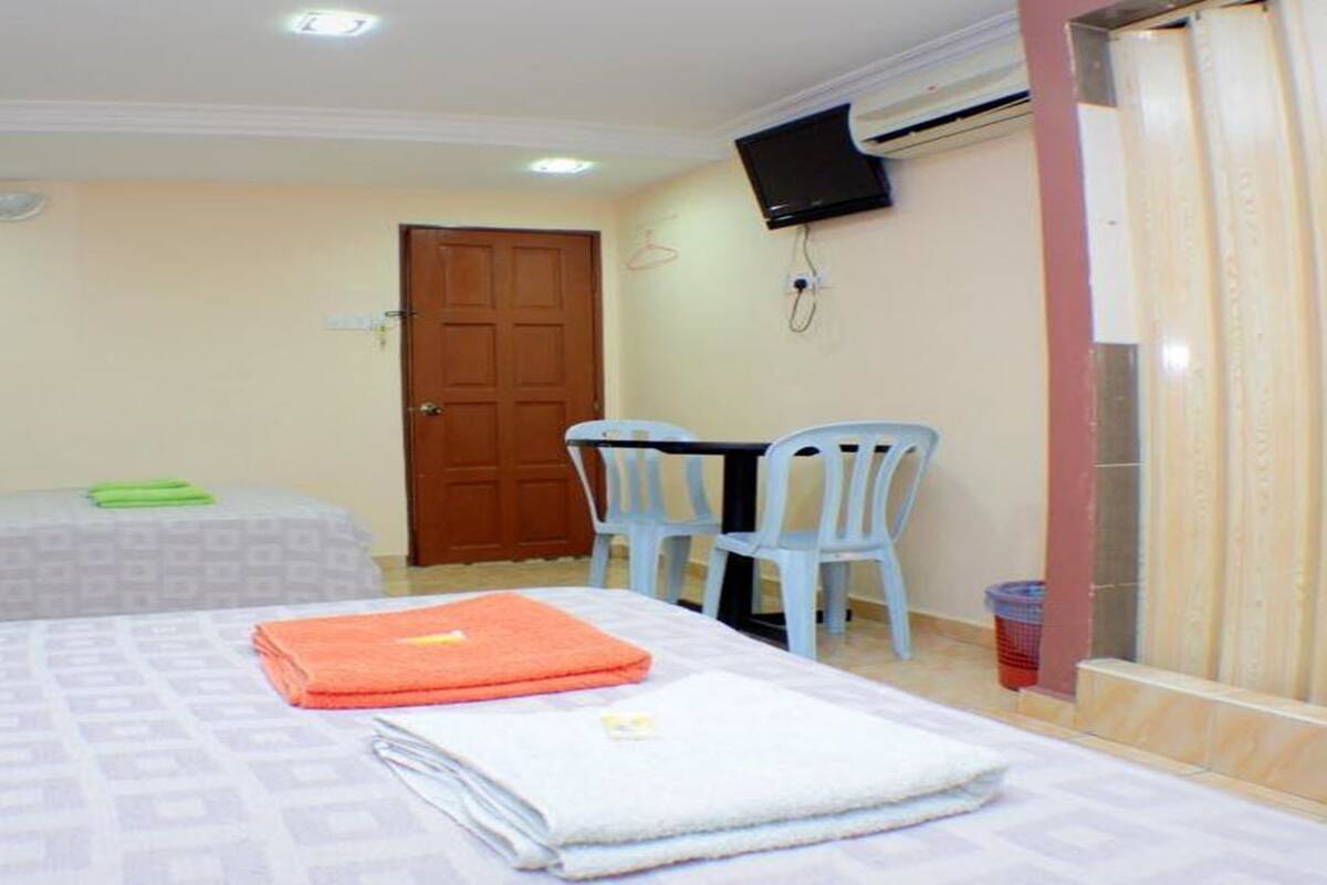 Quarto de hotel com duas camas, uma escrivaninha, uma cadeira e uma televisão.