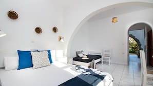 A modern bedroom with a large bed, a smaller bed, and a seating area. - Ktima Bianco (Naxos)