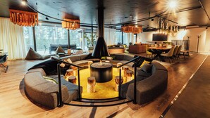 Un salon moderne doté d’un espace salon circulaire, d’un parquet en bois et de grandes fenêtres offrant une vue sur l’extérieur.