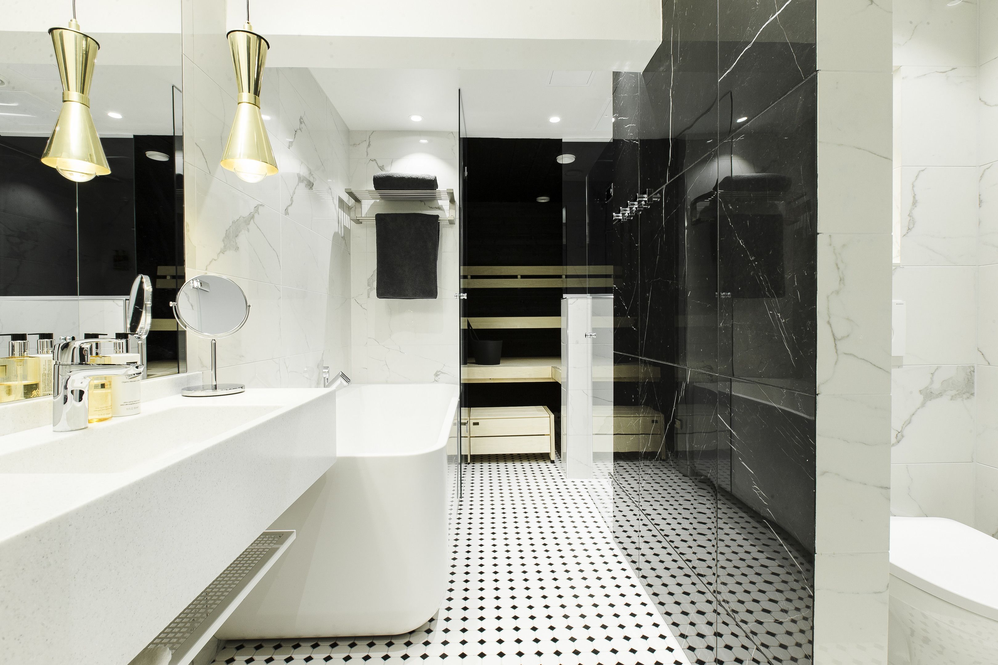 A modern bathroom with a white sink, mirror, and two pendant lights.