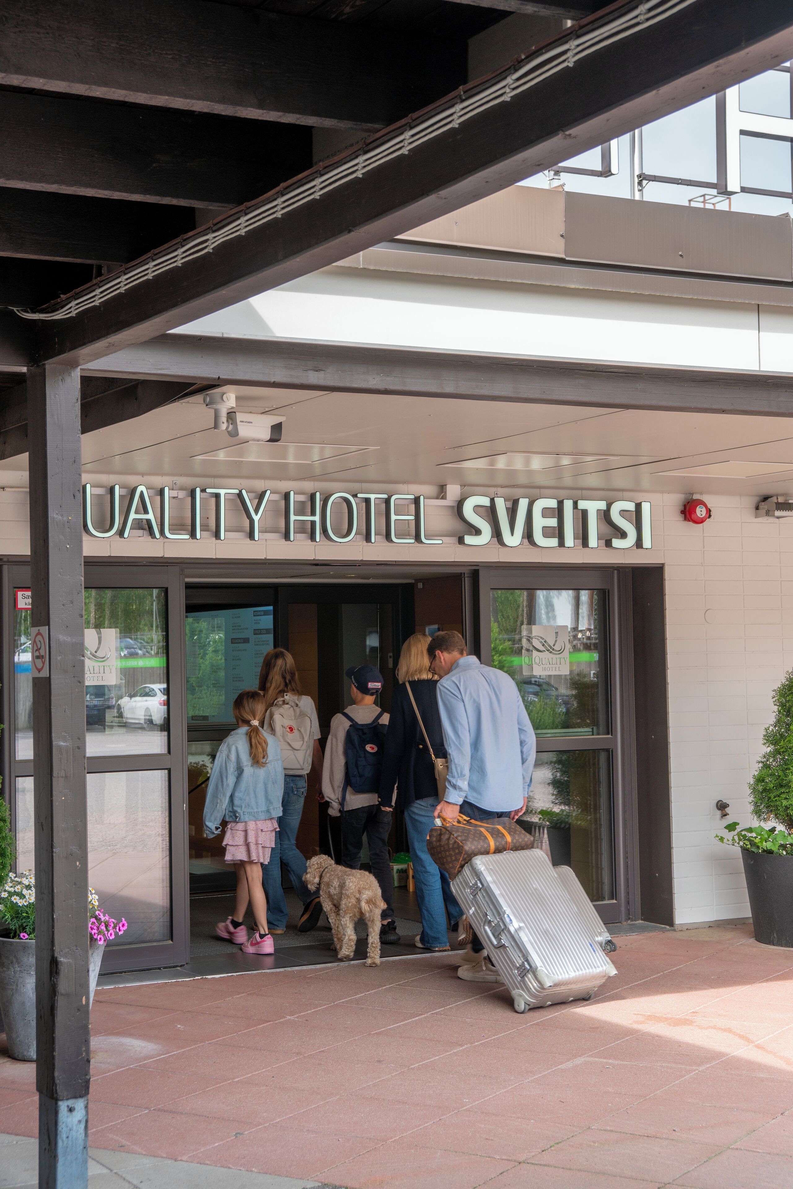 La entrada del HOTEL UALITY SWEITSI, con vista clara del acceso y personas esperando afuera.
