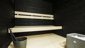 Una sauna con bancos de madera, un cubo y un contenedor de almacenamiento.