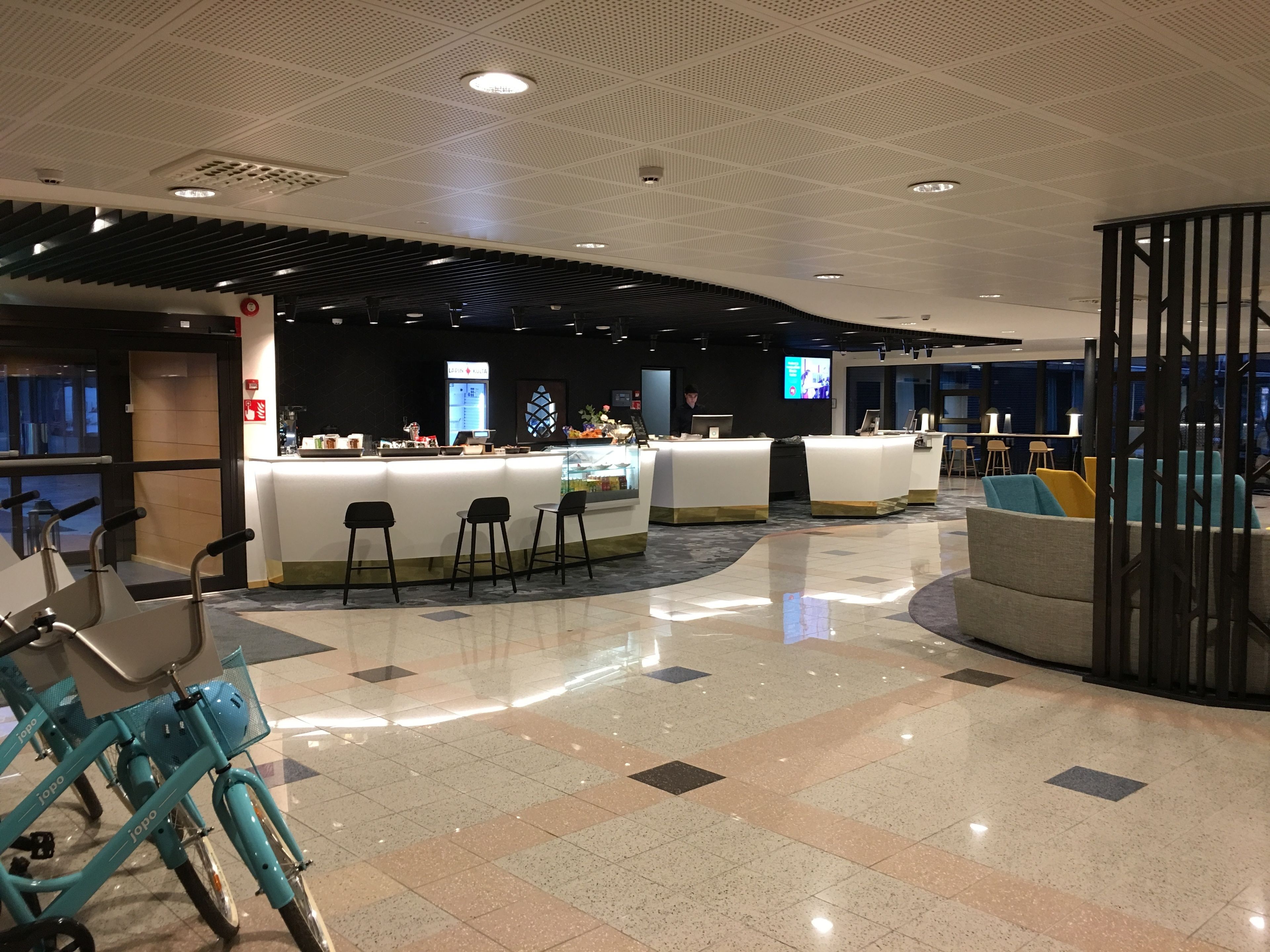 A modern lobby with a reception desk, seating area, and a bike rental station.