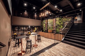 Un interior moderno con una zona de bar, asientos y una escalera que conduce a un nivel superior.