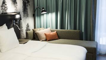 Une chambre d’hôtel avec un lit, un canapé, une lampe et des rideaux.
