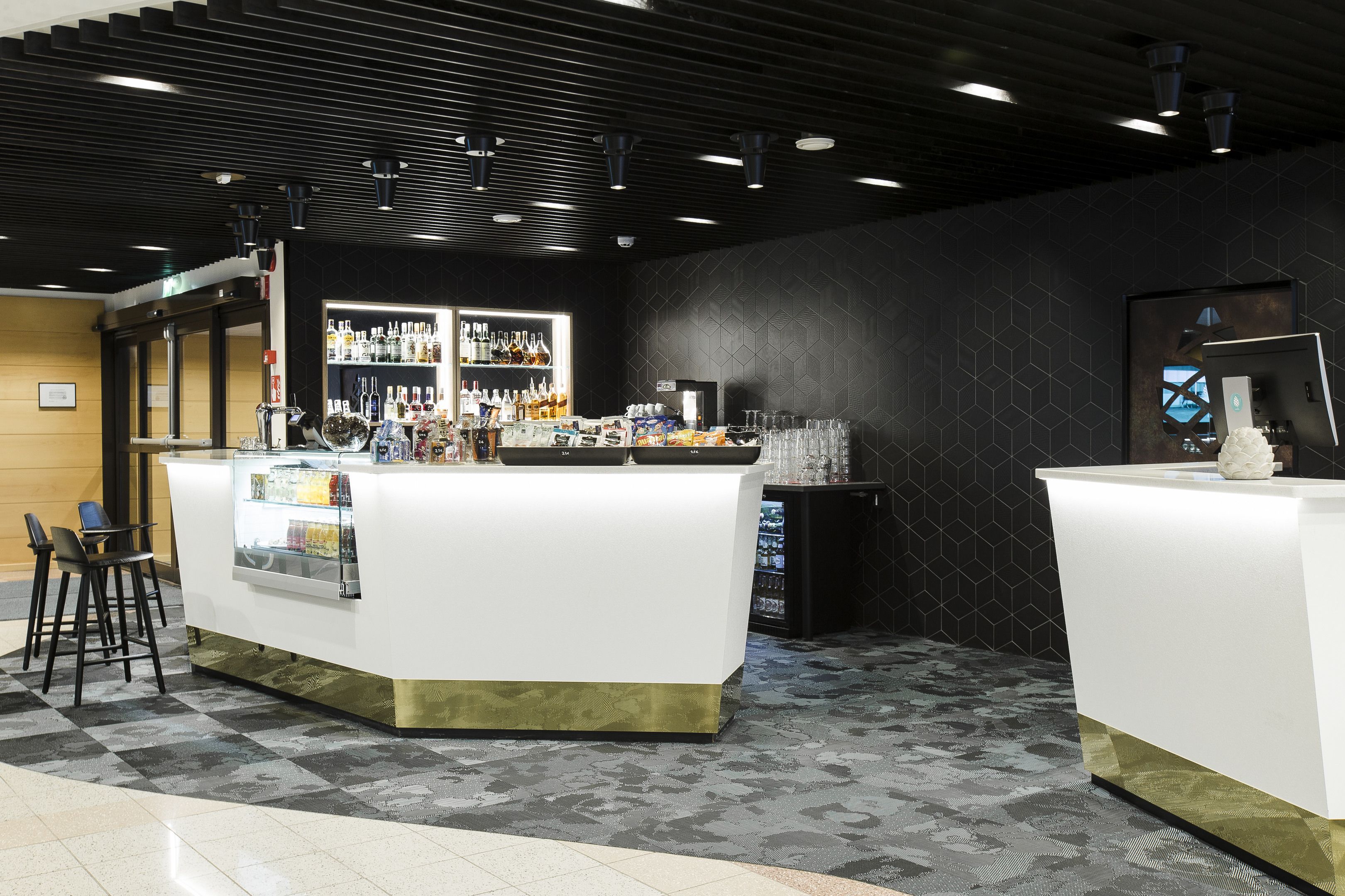 Zona de bar con mostrador, taburetes y una exhibición de botellas.