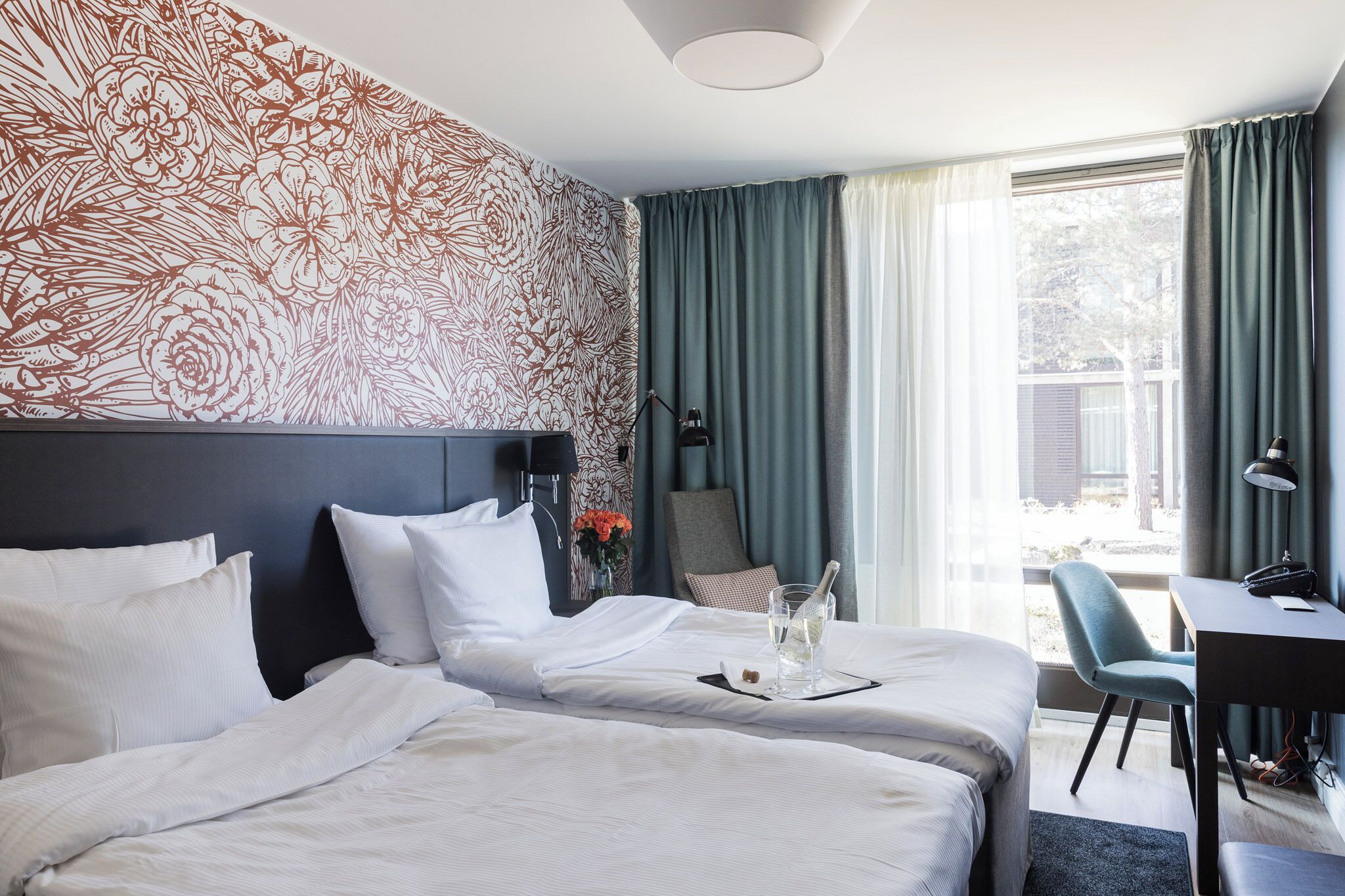 Et hotelværelse med to senge, et skrivebord og en stol.