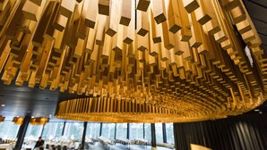 Un interior moderno con un diseño único del techo de madera, un espacio de descanso amplio y ventanas grandes.