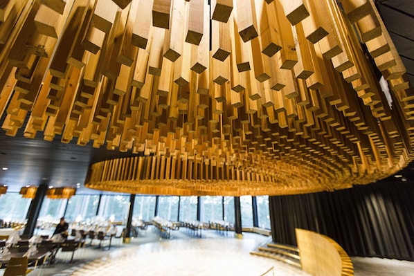 Un interior moderno con un diseño único del techo de madera, un espacio de descanso amplio y ventanas grandes.