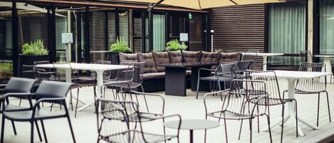 Un área de patio al aire libre con sofá, mesas y sillas.