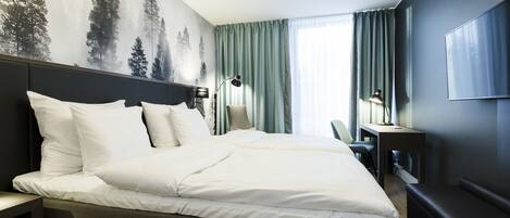 Habitación de hotel con una cama grande, un escritorio, una silla y un televisor.
