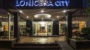 The entrance of Lonicer City with a modern design, featuring a prominent illuminated sign, a spacious entrance area, and a well-lit interior visible through the glass doors. - Lonicera City Hotel (Alanya)