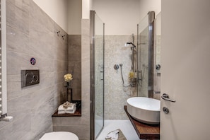 A modern bathroom with a glass-enclosed shower, a white sink, and a towel rack with folded towels. - Approdo Ripetta (Rome)