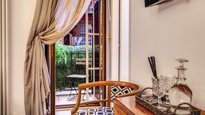 A room with a wooden chair, a table with glassware, and a view of an outdoor balcony with a chair and table. - Approdo Ripetta (Rome)