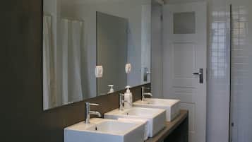 A modern bathroom with two sinks, a large mirror, and pendant lighting.