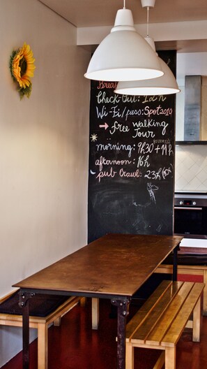 A restaurant interior with a chalkboard menu, wooden tables, and a hanging light fixture. - Porto Spot Hostel (Porto)