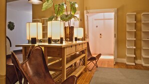 A hotel lobby with a wooden reception desk, leather chairs, a potted plant, and a bookshelf.