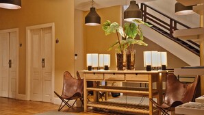 A dining area with a wooden table, leather chairs, and a staircase in the background.