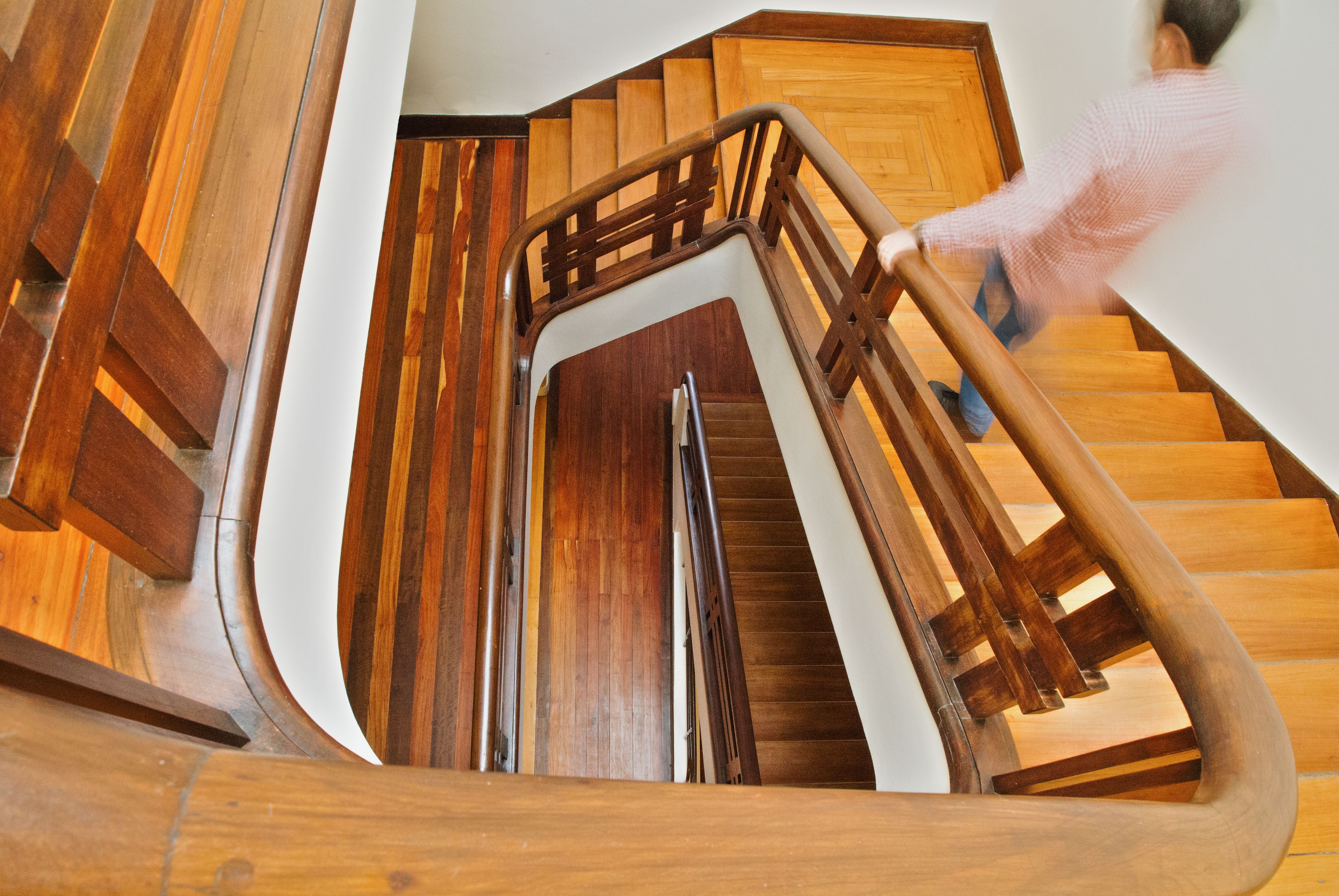 A wooden staircase with a curved design and a metal handrail.