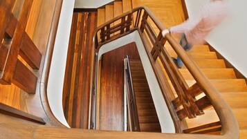 A wooden staircase with a curved design and a metal handrail.