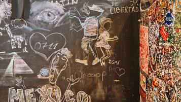 A wall with various drawings and writings, including a large eye, a heart, and the word "MEXICO".