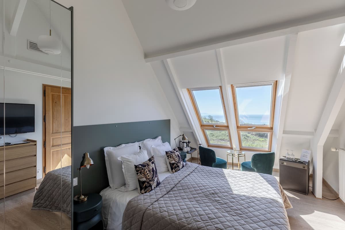 A bedroom with a large bed, a desk, a chair, and a TV.