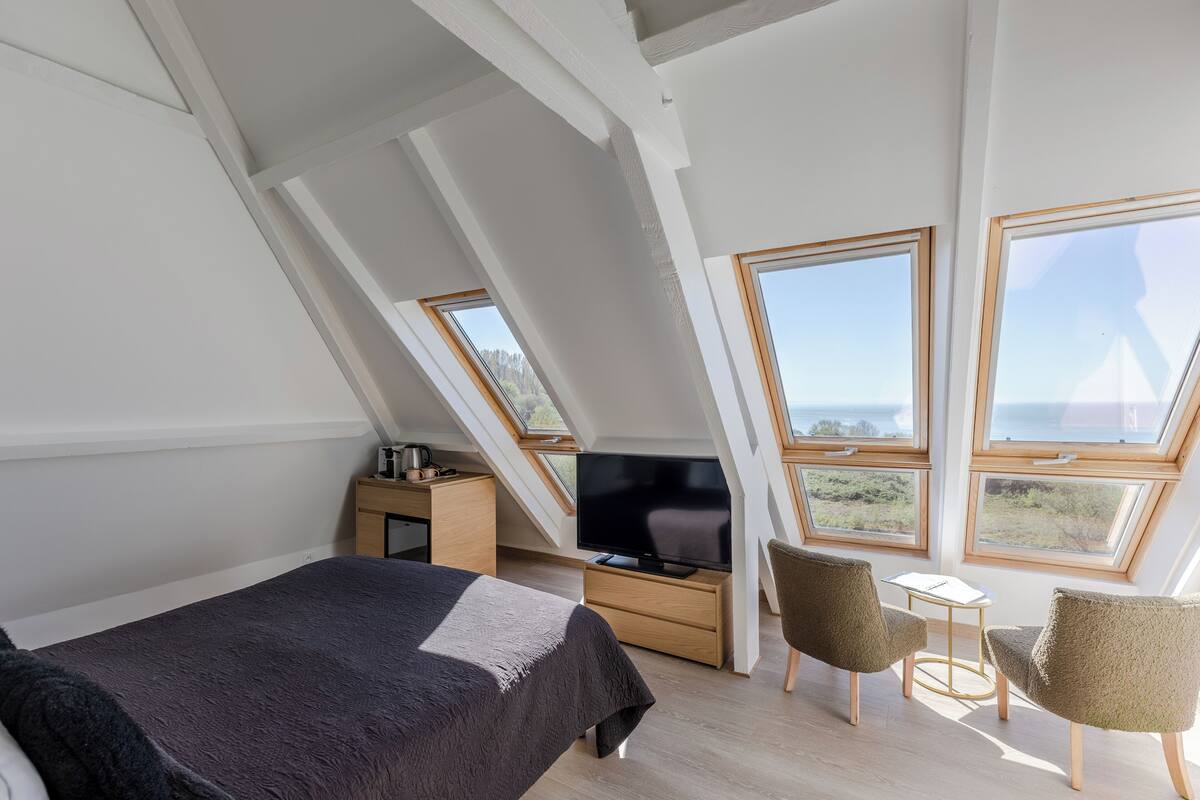 A bedroom with a bed, a TV, a desk, and two chairs.